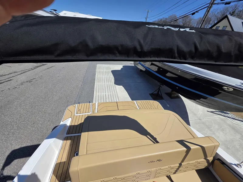 Slide: The Image of 2025 Sea Ray 210SPX boat with tan seating and black canopy, parked on pavement. - 4