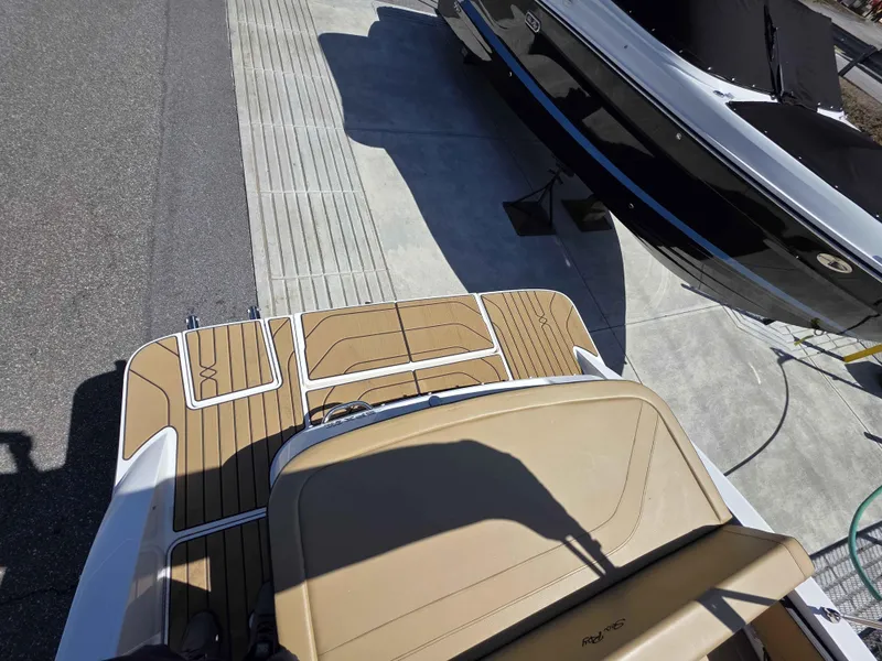 Slide: The Image of 2025 Sea Ray 210SPX boat with tan deck and black hull, parked on concrete. - 5