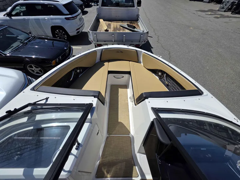Slide: The Image of 2025 Sea Ray 210SPX boat interior with tan seating, parked near vehicles. - 9