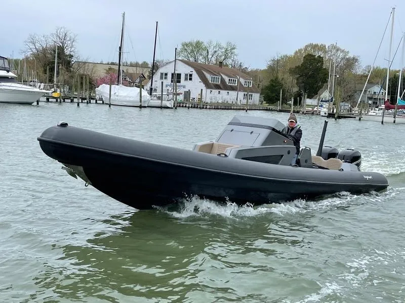 Slide: The Image of Roughneck 1010 boat cruising on water, 2022 model, near a marina with docked boats. - 7