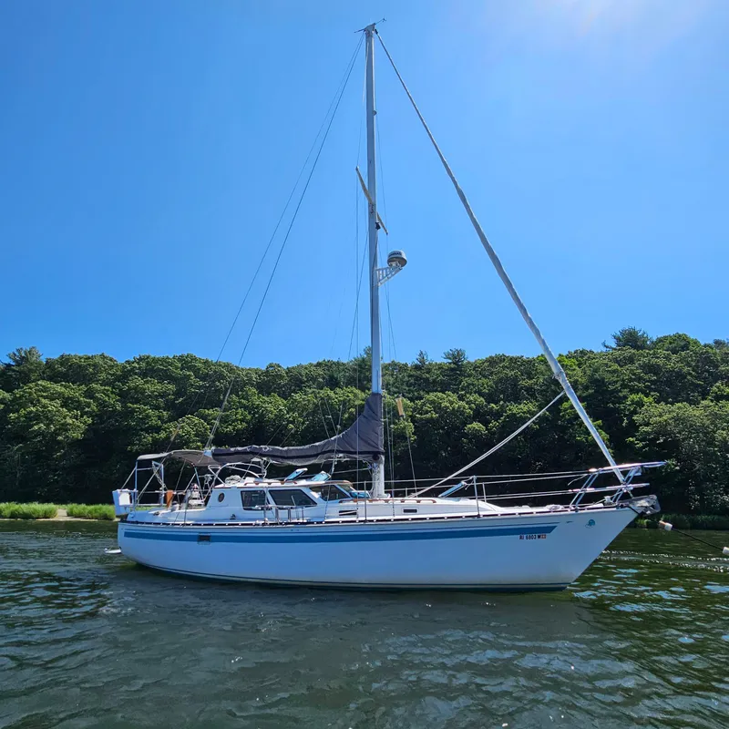 Slide: The Image of 1986 Nautilus Pilothouse 36 sailboat on calm water, surrounded by lush greenery. - 1