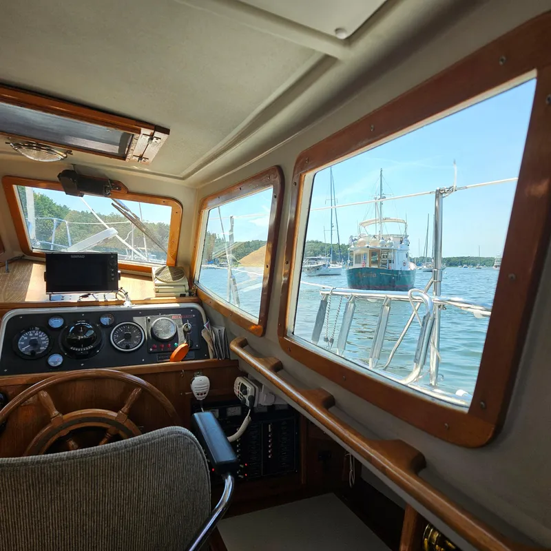 Slide: The Image of Interior view of 1986 Nautilus Pilothouse 36, showcasing helm and windows overlooking marina. - 15