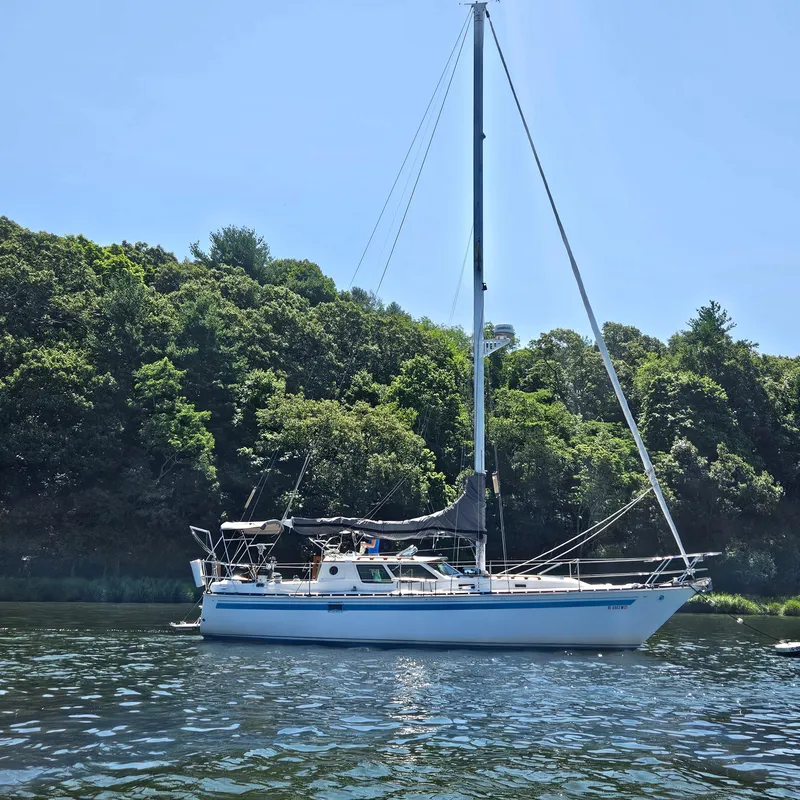 Slide: The Image of 1986 Nautilus Pilothouse 36 sailboat on calm water, surrounded by lush greenery. - 2