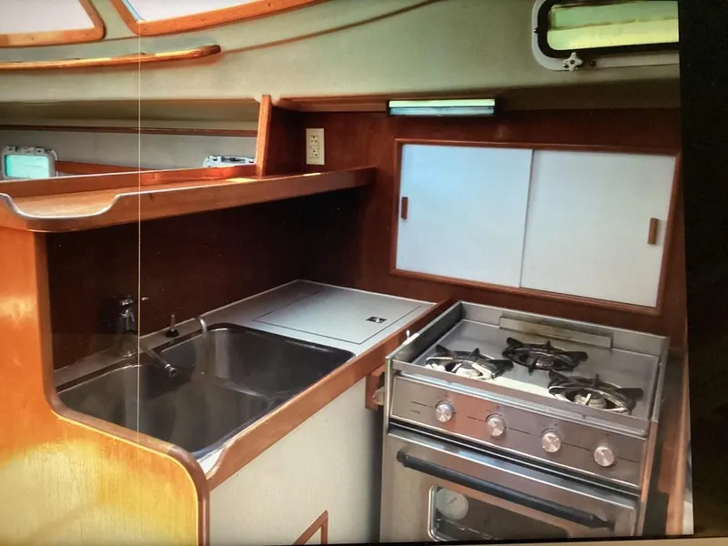 Slide: The Image of 1986 Nautilus Pilothouse 36 kitchen with stove, sink, and wooden cabinetry. - 20