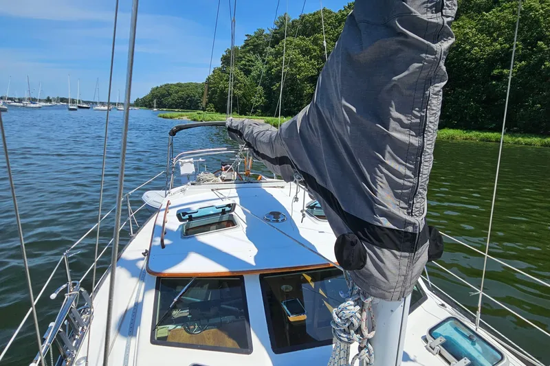Slide: The Image of 1986 Nautilus Pilothouse 36 sailboat on calm water, surrounded by lush greenery. - 48