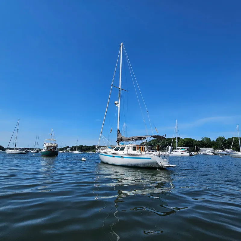 Slide: The Image of Sailboat Nautilus Pilothouse 36, 1986, anchored in a serene harbor under clear blue skies. - 6