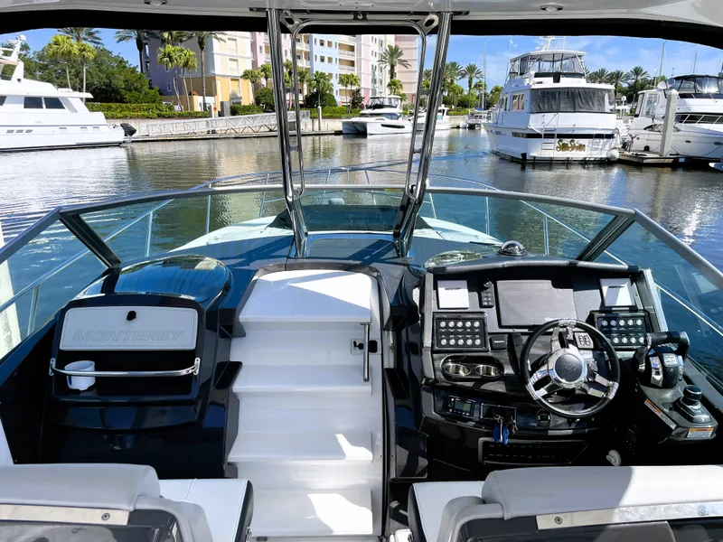 Slide: The Image of 2020 Monterey 345 Sport Yacht cockpit with marina view, featuring modern controls and seating. - 32