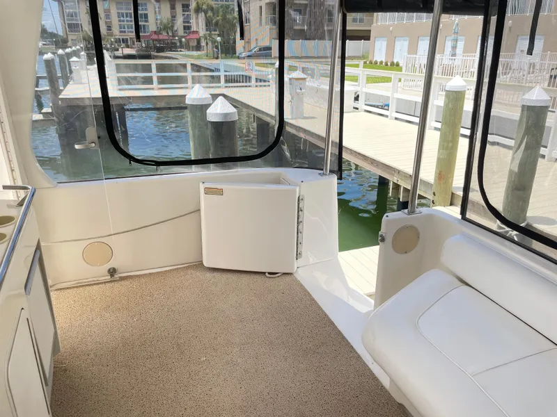 Slide: The Image of 1998 Sea Ray 420 Aft Cabin interior with dock view, featuring white seating and carpeted floor. - 18