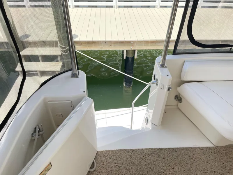 Slide: The Image of 1998 Sea Ray 420 Aft Cabin boat interior with dock view, featuring white seating and railing. - 19