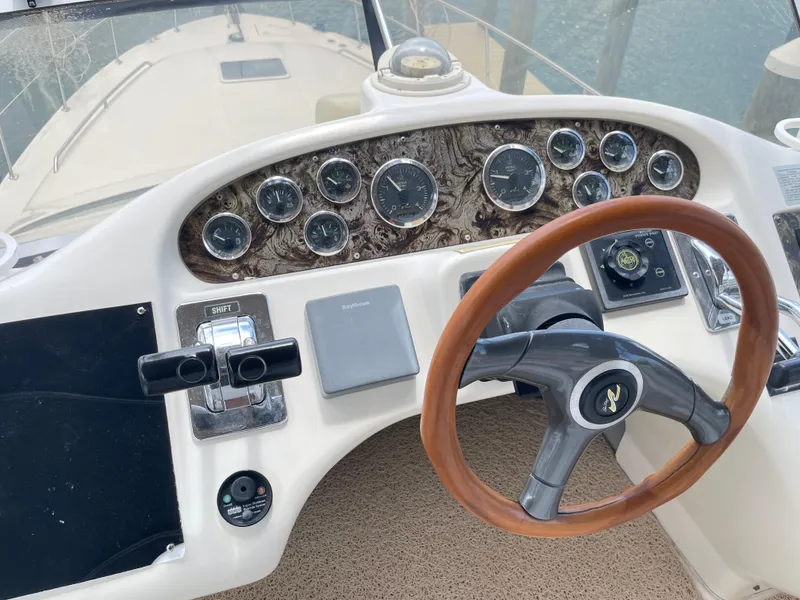 Slide: The Image of 1998 Sea Ray 420 Aft Cabin helm with gauges, wooden steering wheel, and control panel. - 33