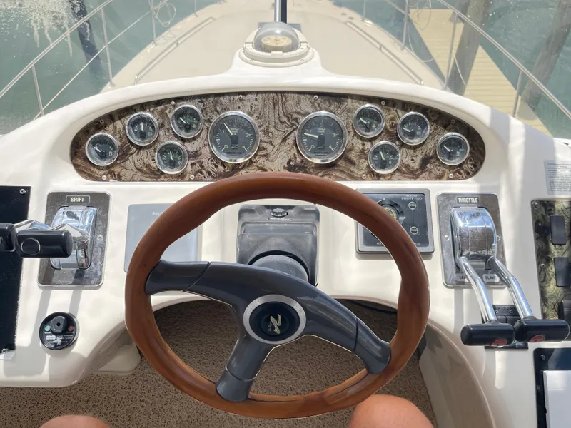Slide: The Image of 1998 Sea Ray 420 Aft Cabin helm with gauges, wooden steering wheel, and throttle controls. - 39