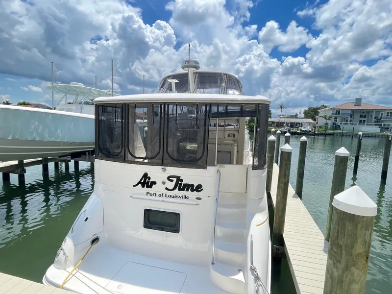 Slide: The Image of 1998 Sea Ray 420 Aft Cabin yacht docked, named "Air Time," under a partly cloudy sky. - 4
