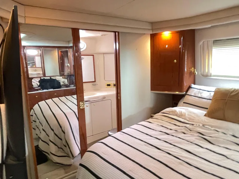 Slide: The Image of 1998 Sea Ray 420 Aft Cabin interior with cozy bedroom and striped bedding. - 46
