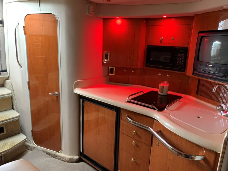 Slide: The Image of 2001 Sea Ray 340 Amberjack cabin kitchen with red lighting, microwave, TV, and sink. - 15