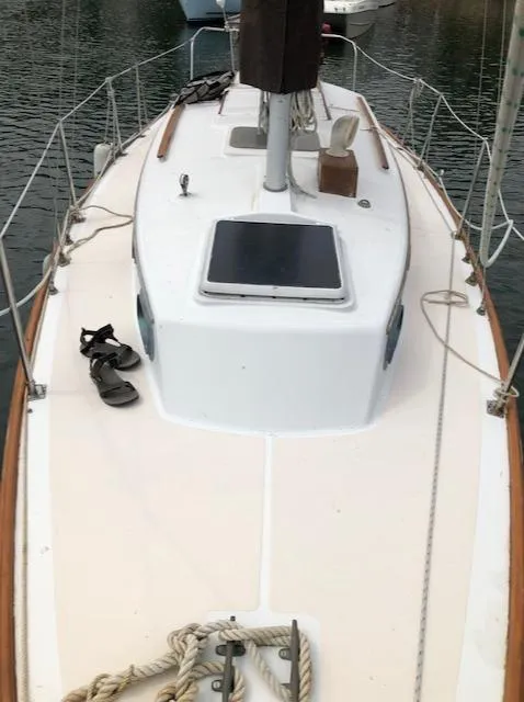 Slide: The Image of 1983 Cape Dory 28 sailboat deck with hatch and ropes, docked on calm water. - 10