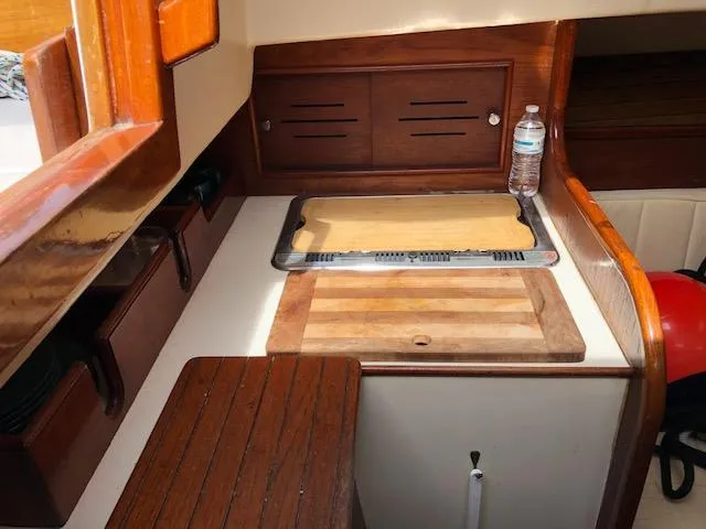 Slide: The Image of 1983 Cape Dory 28 interior galley with wooden cabinetry and cutting board. - 26