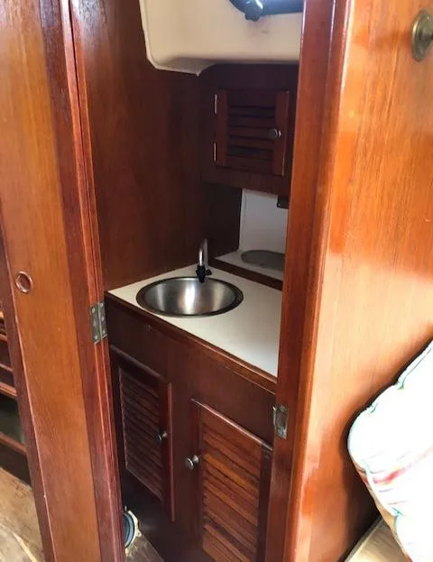Slide: The Image of 1983 Cape Dory 28 sailboat interior with compact wooden kitchenette and stainless steel sink. - 30