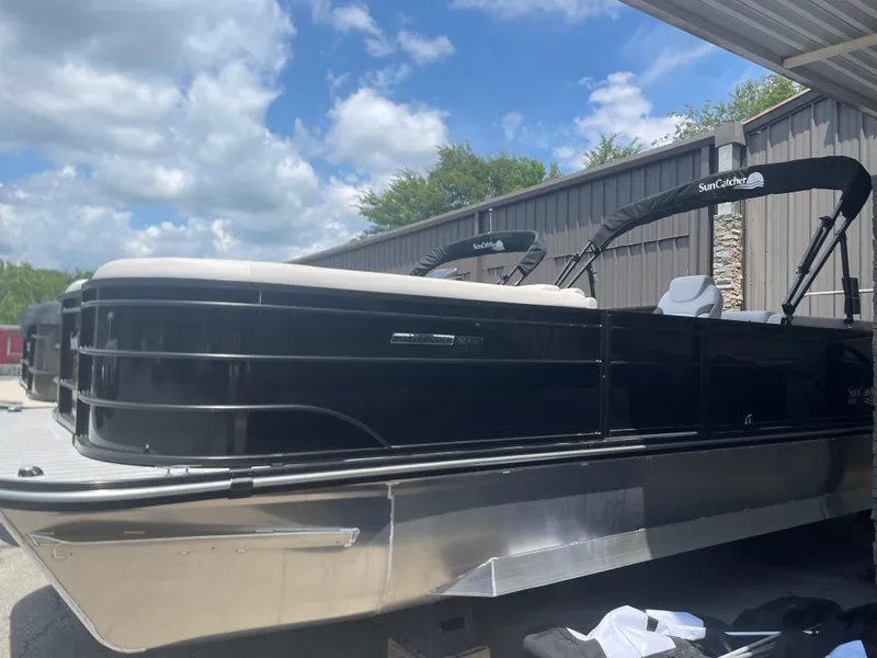 Slide: The Image of 2024 SunCatcher Select 324RC pontoon boat in black, docked under a canopy. - 0