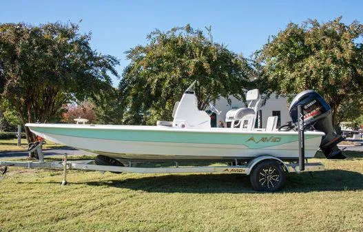 Slide: The Image of 2024 Avid 21 FSX boat on a trailer, parked on grass. - 1