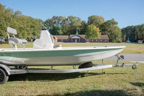 Slide: The Image of 2024 Avid 21 FSX boat on trailer in grassy area with buildings in background. - 26