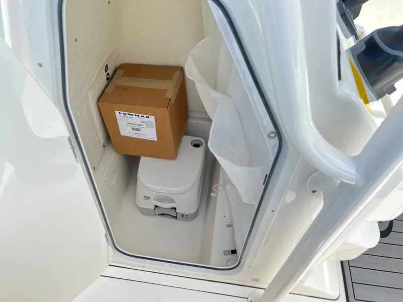 Slide: The Image of 2025 Key West 244 CC boat storage compartment with portable toilet and box. - 29