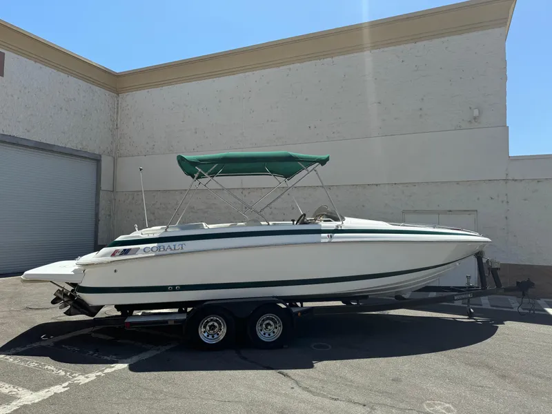 The Image of 2001 Cobalt 25 LS boat with green canopy on trailer in parking lot. - 0