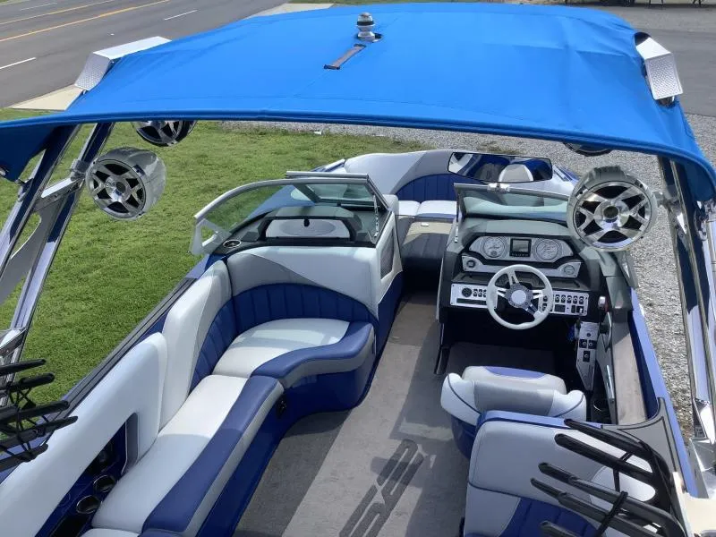 Slide: The Image of 2016 MB B52 23 boat interior with blue and white seating, blue canopy, and modern dashboard. - 22