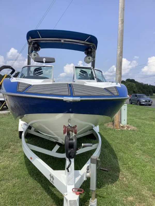 Slide: The Image of 2016 MB B52 23 boat on trailer, blue and white, parked on grass. - 3