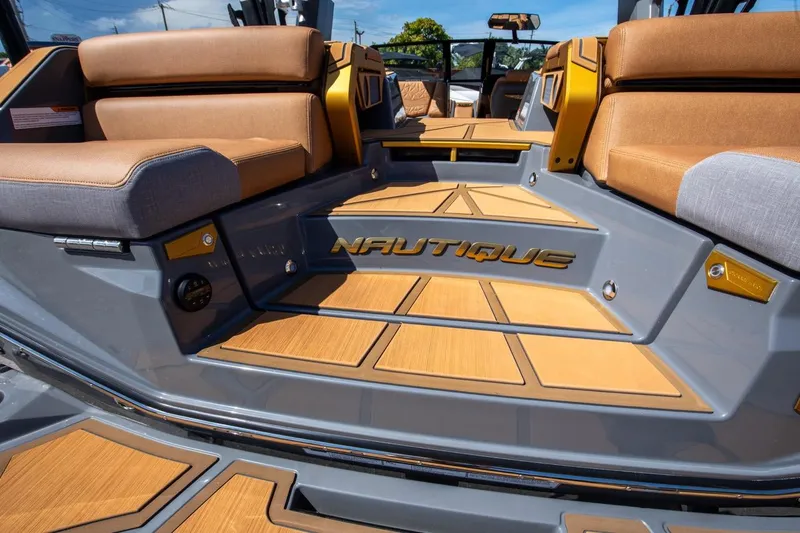Slide: The Image of 2024 Nautique G23 boat interior with tan and gray seating, teak flooring. - 16