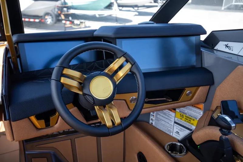 Slide: The Image of 2024 Nautique G23 boat dashboard with gold-accented steering wheel and modern controls. - 24