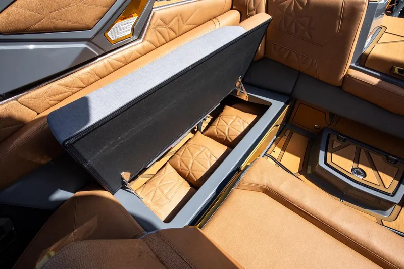 Slide: The Image of 2024 Nautique G23 boat interior with open storage compartment and tan upholstery. - 38
