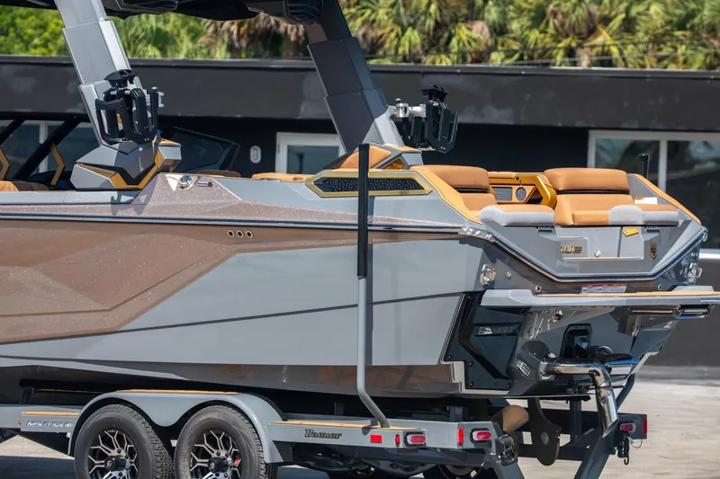 Slide: The Image of 2024 Nautique G23 boat on trailer, rear view with tan seats and modern design. - 8