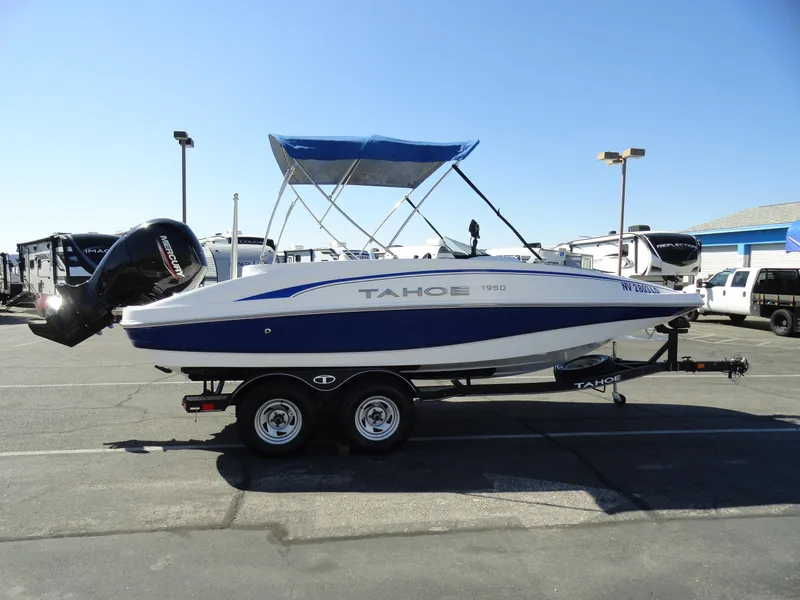 Slide: The Image of 2020 Tahoe 1950 boat with blue canopy on trailer in parking lot. - 4