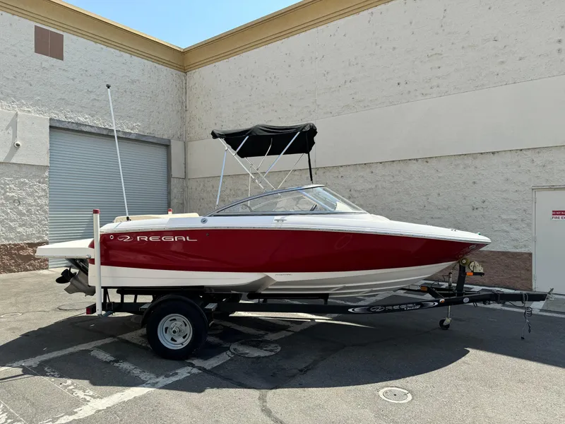 The Image of 2019 Regal 1900 ES Bowrider boat on a trailer in a parking lot. - 1