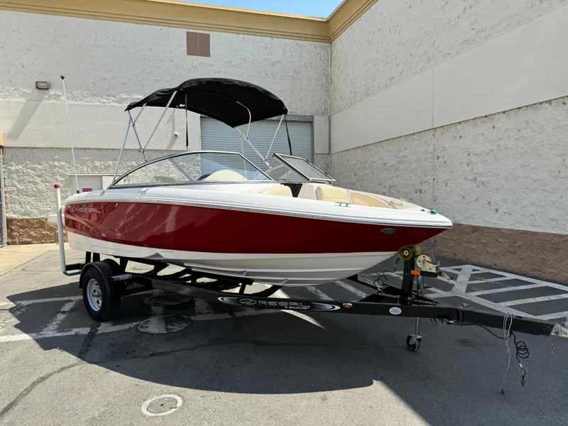 Slide: The Image of 2019 Regal 1900 ES Bowrider boat on trailer, red and white exterior, parked outdoors. - 2