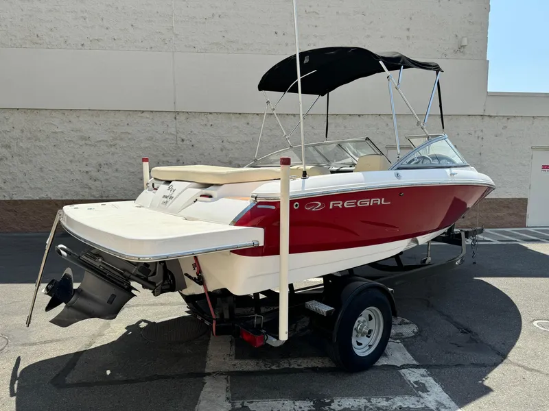 Slide: The Image of 2019 Regal 1900 ES Bowrider boat with red and white exterior on a trailer. - 7
