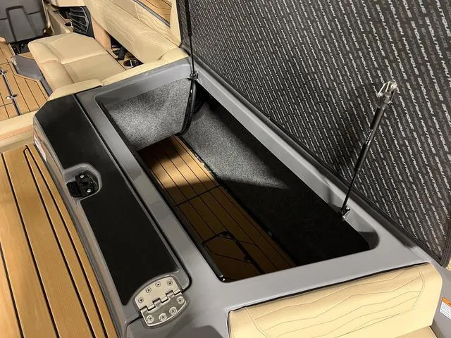 Slide: The Image of 2025 Nautique Super Air Nautique G23 storage compartment with open lid and beige seating. - 10