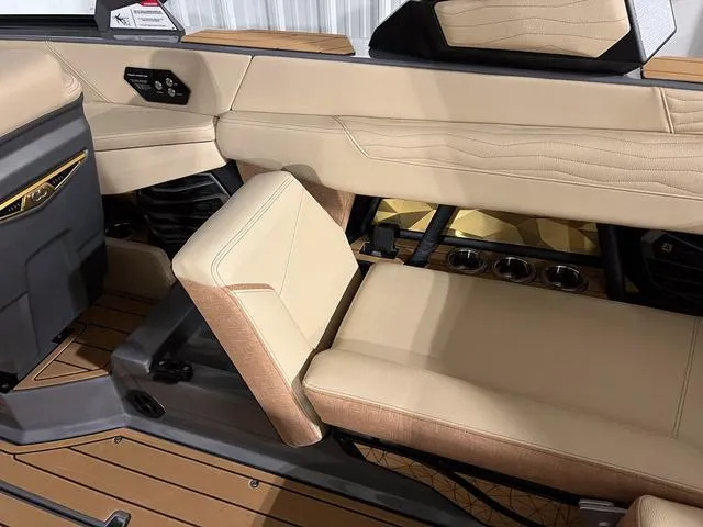 Slide: The Image of 2025 Nautique Super Air Nautique G23 interior seating with beige upholstery and cup holders. - 16