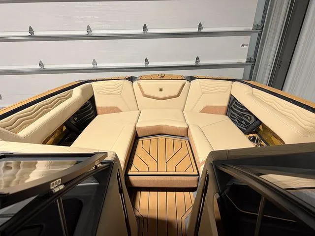 Slide: The Image of 2025 Nautique Super Air Nautique G23 boat interior with beige seating and wood flooring. - 28
