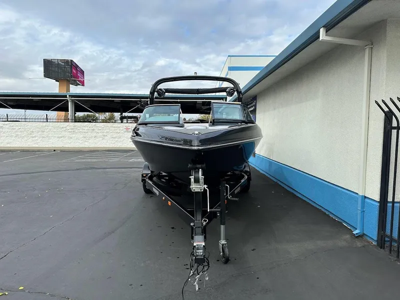 Slide: The Image of 2024 Sanger V237 SX boat parked on a trailer near a building. - 2