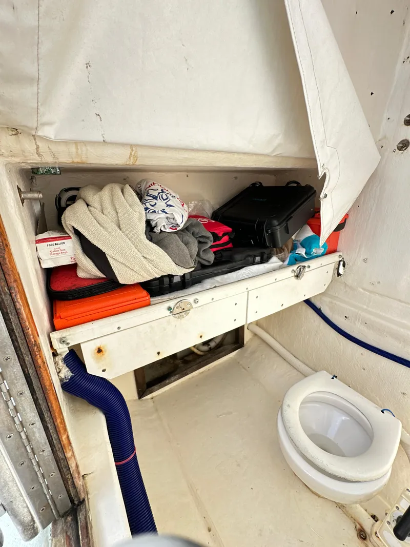 Slide: The Image of 1988 Ocean Master 31 Center Console boat interior with storage and marine toilet. - 32