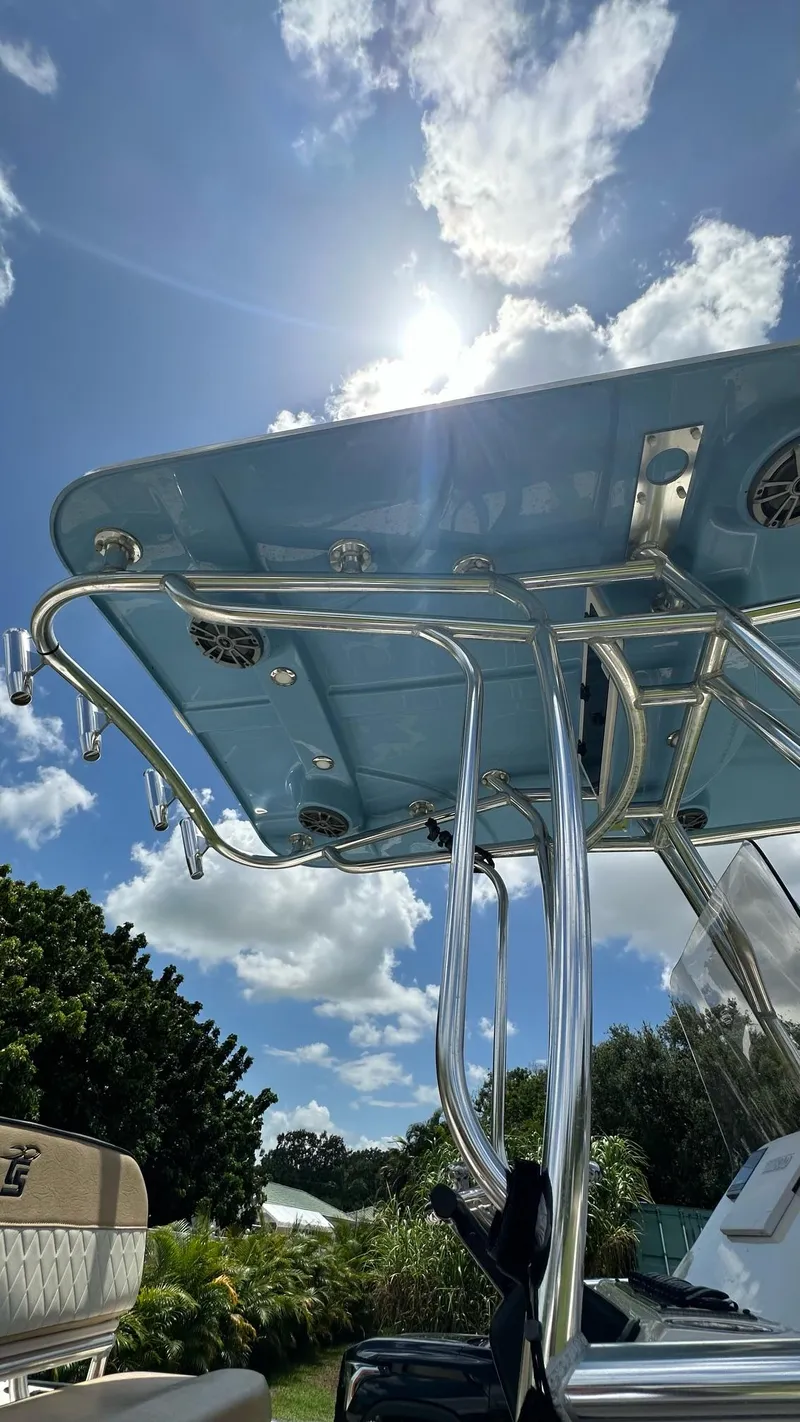 Slide: The Image of 2023 Carolina Skiff 24 Ultra Elite boat under sunny sky with T-top and rod holders. - 25