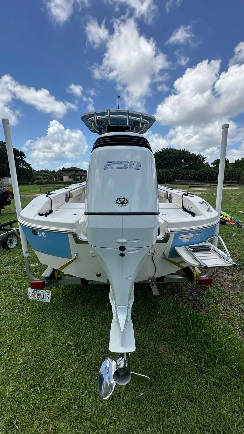 Slide: The Image of 2023 Carolina Skiff 24 Ultra Elite boat, rear view, on grass under a blue sky. - 6