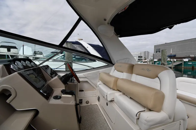 Slide: The Image of 2009 Sea Ray 330 Sundancer interior with helm, seating, and marina view. - 14