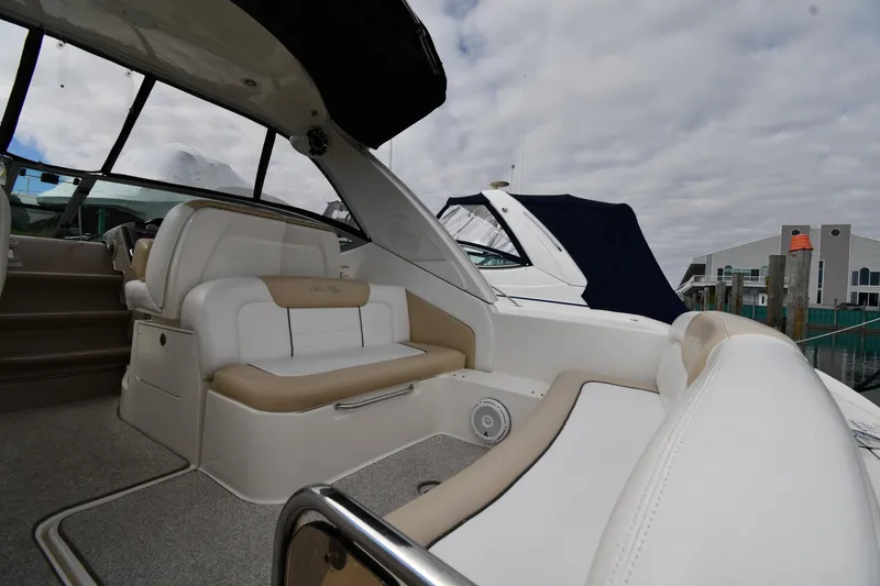 Slide: The Image of 2009 Sea Ray 330 Sundancer interior with beige seating and marina backdrop. - 16