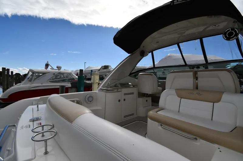 Slide: The Image of 2009 Sea Ray 330 Sundancer interior with seating, docked at marina under blue sky. - 17