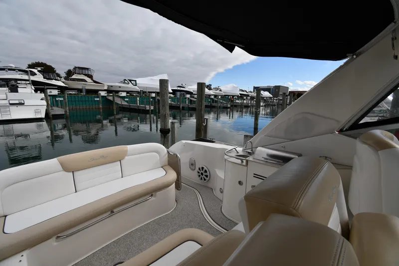 Slide: The Image of 2009 Sea Ray 330 Sundancer interior with marina view, featuring beige seating and calm waters. - 18