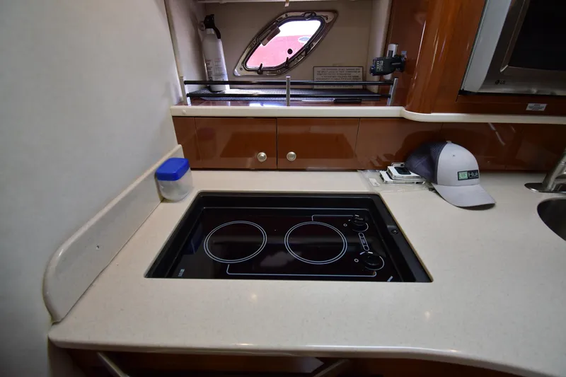 Slide: The Image of 2009 Sea Ray 330 Sundancer kitchen with stovetop, countertop, and window view. - 35