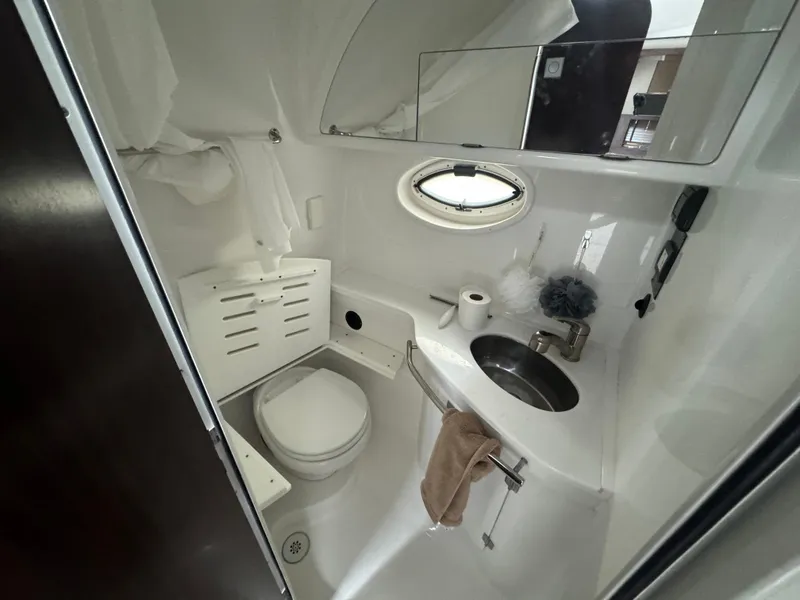 Slide: The Image of 2019 Monterey 335 SY boat bathroom with toilet, sink, and porthole window. - 38