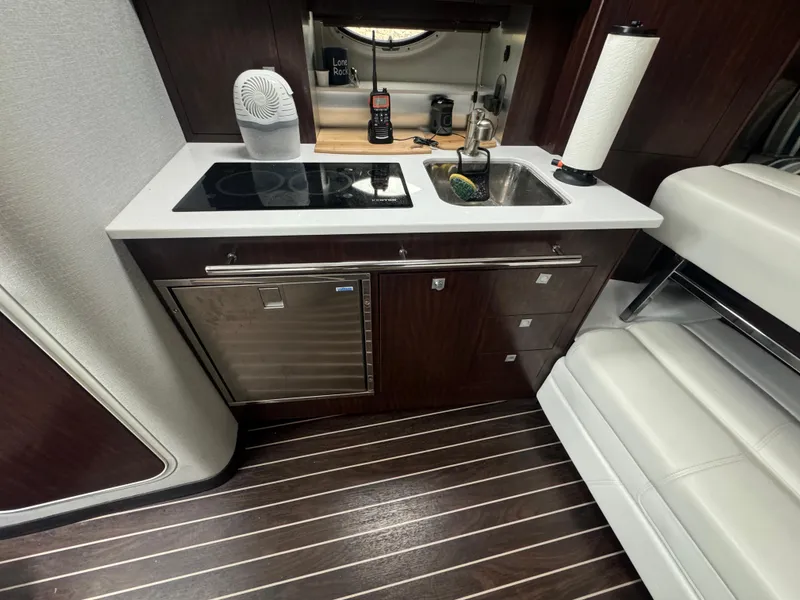 Slide: The Image of 2019 Monterey 335 SY yacht interior kitchen with stove, sink, and dark wood cabinetry. - 39
